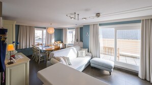 Une chambre d’hôtel avec un lit, un bureau, une chaise, une table et un balcon avec vue.