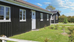A single-story black building with a tiled roof, a white door, and multiple windows. - 6 Person Holiday Home in Rodvig Stevns (Rodvig Stevns)