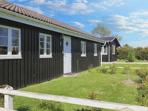A single-story black building with a tiled roof, a white door, and multiple windows. - 6 Person Holiday Home in Rodvig Stevns (Rodvig Stevns)