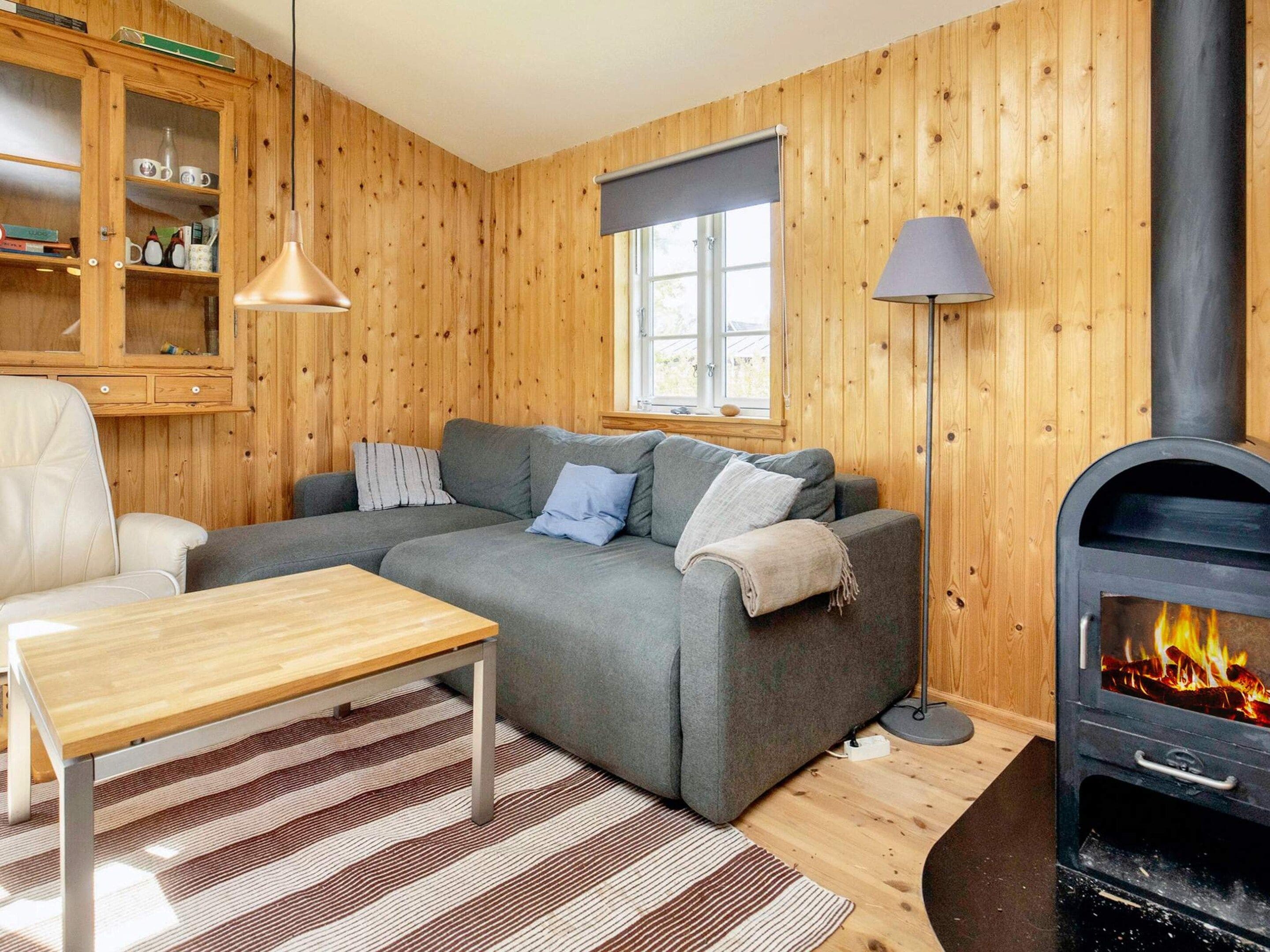 Un salon chaleureux avec un canapé, une table, une lampe, une cheminée et des murs en bois.
