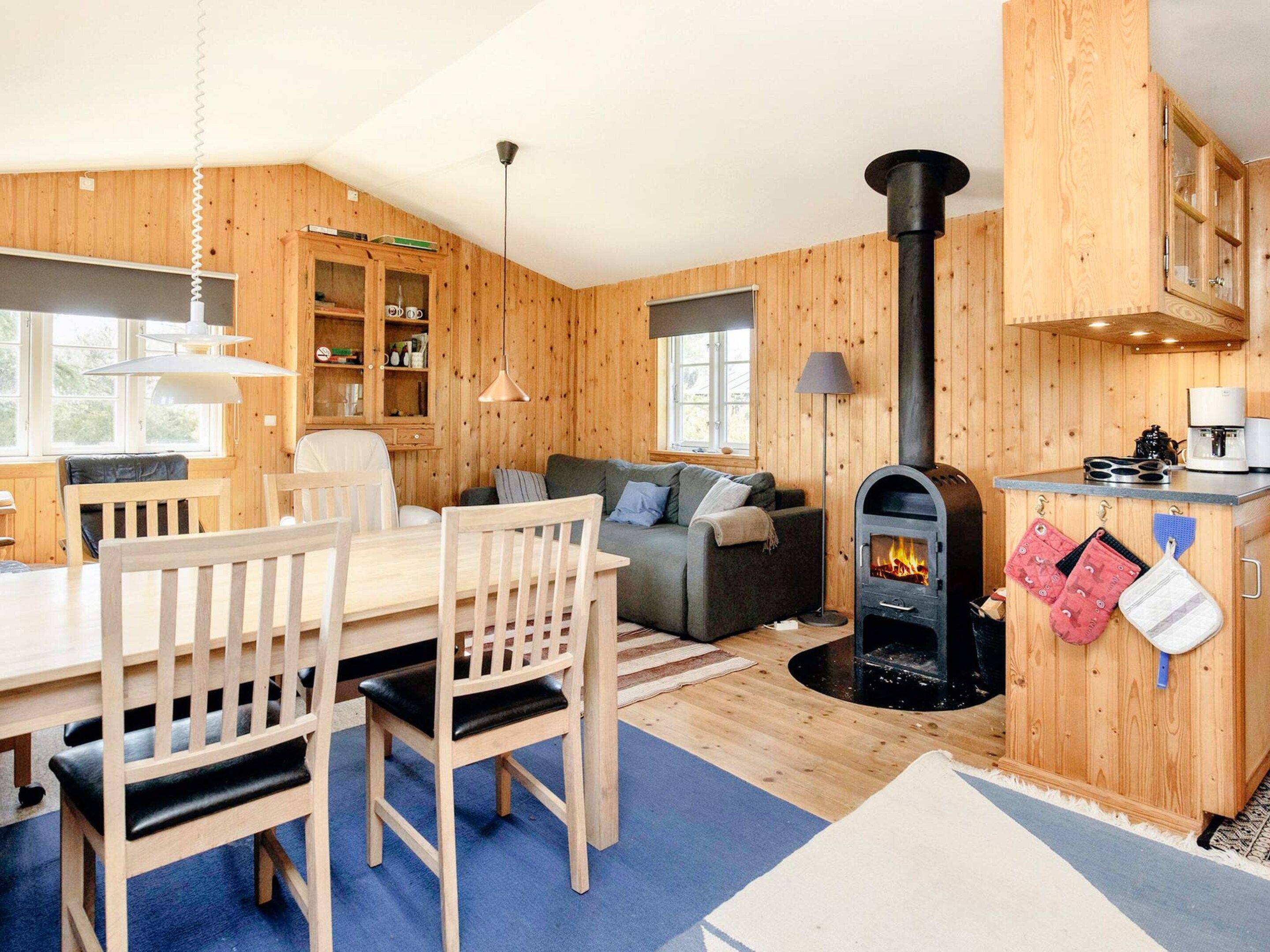 Un intérieur de chalet chaleureux avec un coin repas, un canapé, une cheminée et des meubles en bois.