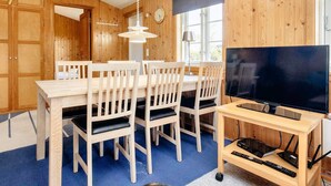 A wooden-paneled room with a dining table, chairs, a television, and a lamp. - 6 Person Holiday Home in Rodvig Stevns (Rodvig Stevns)