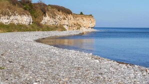 A pebbly beach with a rocky cliff in the background. - 6 Person Holiday Home in Rodvig Stevns (Rodvig Stevns)