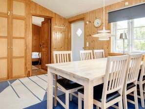 A wooden-paneled room with a dining table, chairs, a coat rack, and a clock on the wall. - 6 Person Holiday Home in Rodvig Stevns (Rodvig Stevns)