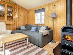 A cozy living room with a sofa, a table, a lamp, and a wood-burning stove. - 6 Person Holiday Home in Rodvig Stevns (Rodvig Stevns)