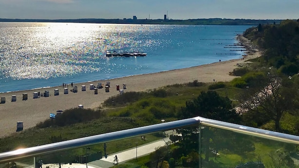 A beach with a boat, a clear sky, and a distant city skyline. - Lovely Apartment in Neustadt (Neustadt in Holstein)