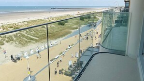 Blick vom Balkon auf den Strand, mit freier Sicht auf den Strand, einen Steg und ein Riesenrad in der Ferne.