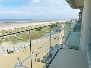 Blick vom Balkon auf den Strand, mit freier Sicht auf den Strand, einen Steg und ein Riesenrad in der Ferne.