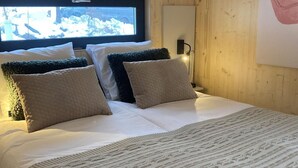 A bed with white linens, two beige pillows, and a textured blanket.