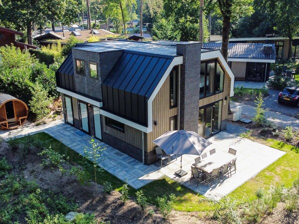 A modern house with a sloped roof, large windows, and a patio with outdoor furniture.