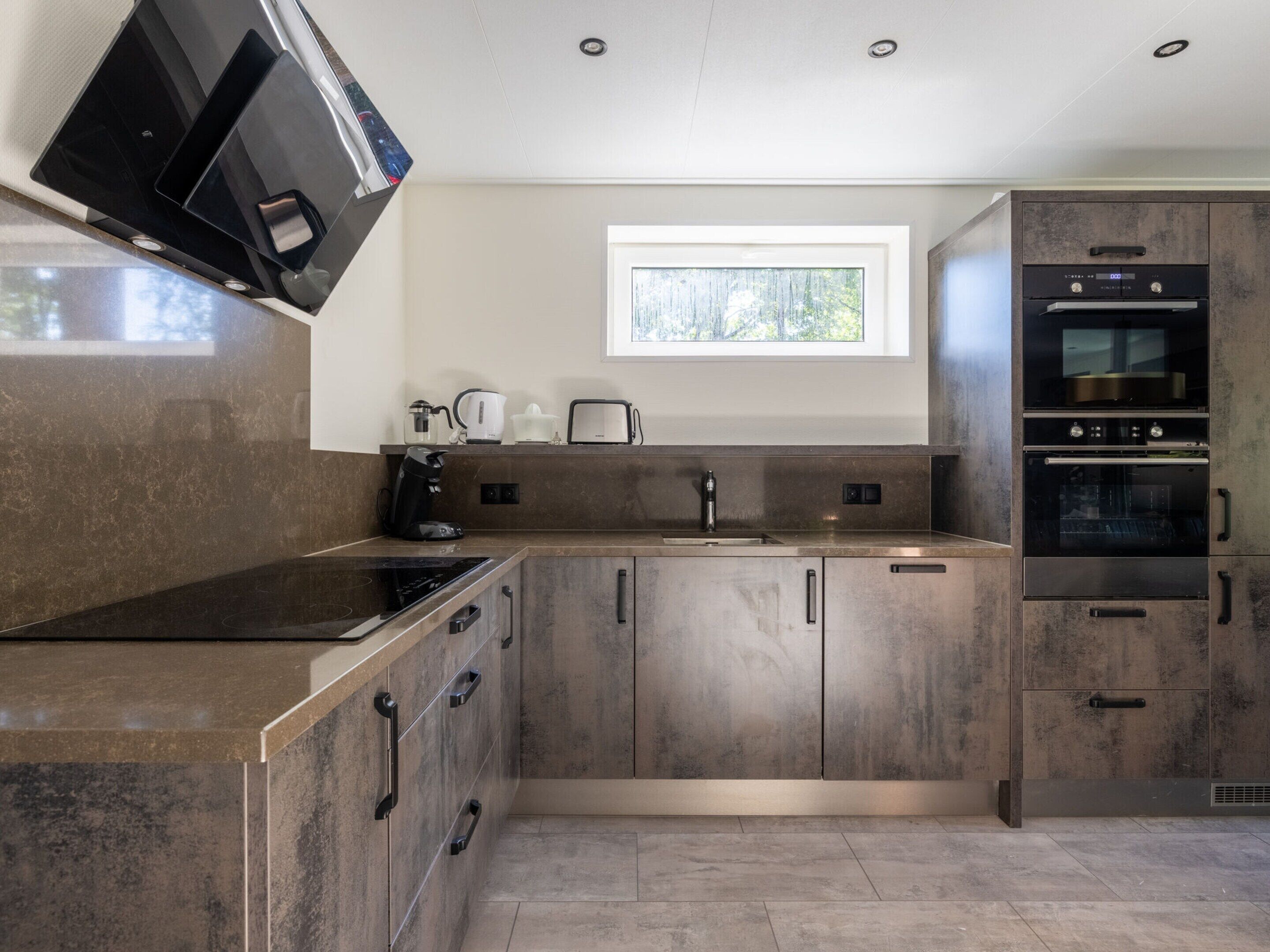A modern kitchen with a built-in microwave, toaster, and oven.