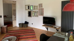 Ett modernt vardagsrum med en tv, en röd hänglampa och en randig matta.