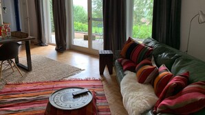 Ett vardagsrum med en grön soffa, en randig matta och en fjärrkontroll på ett brickbord.