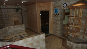 A spa area with a wooden sauna, a small sink, and a clock on the wall. - Postwiese Comfortable Holiday Residence (Winterberg)