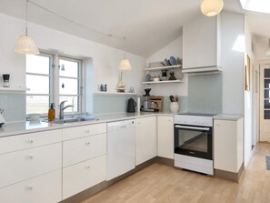 A modern kitchen with white cabinets, a built-in oven, and pendant lights. - 10 Person Holiday Home in Harboore (Harboore)