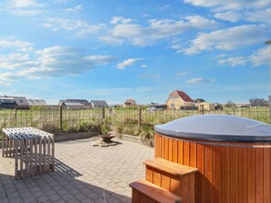 A patio area with a hot tub, wooden benches, and a fire pit. - 10 Person Holiday Home in Harboore (Harboore)