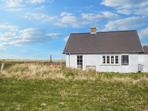 A single-story house with a grey roof and white walls, surrounded by a grassy field and a fence. - 10 Person Holiday Home in Harboore (Harboore)