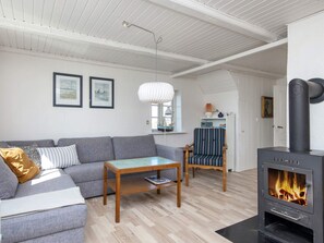 A modern living room with a sofa, a wooden coffee table, a striped armchair, a fireplace, and framed artwork on the wall. - 10 Person Holiday Home in Harboore (Harboore)