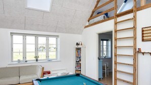 A room with a pool table, a sofa, a bookshelf, and a loft area with a ladder. - 10 Person Holiday Home in Harboore (Harboore)