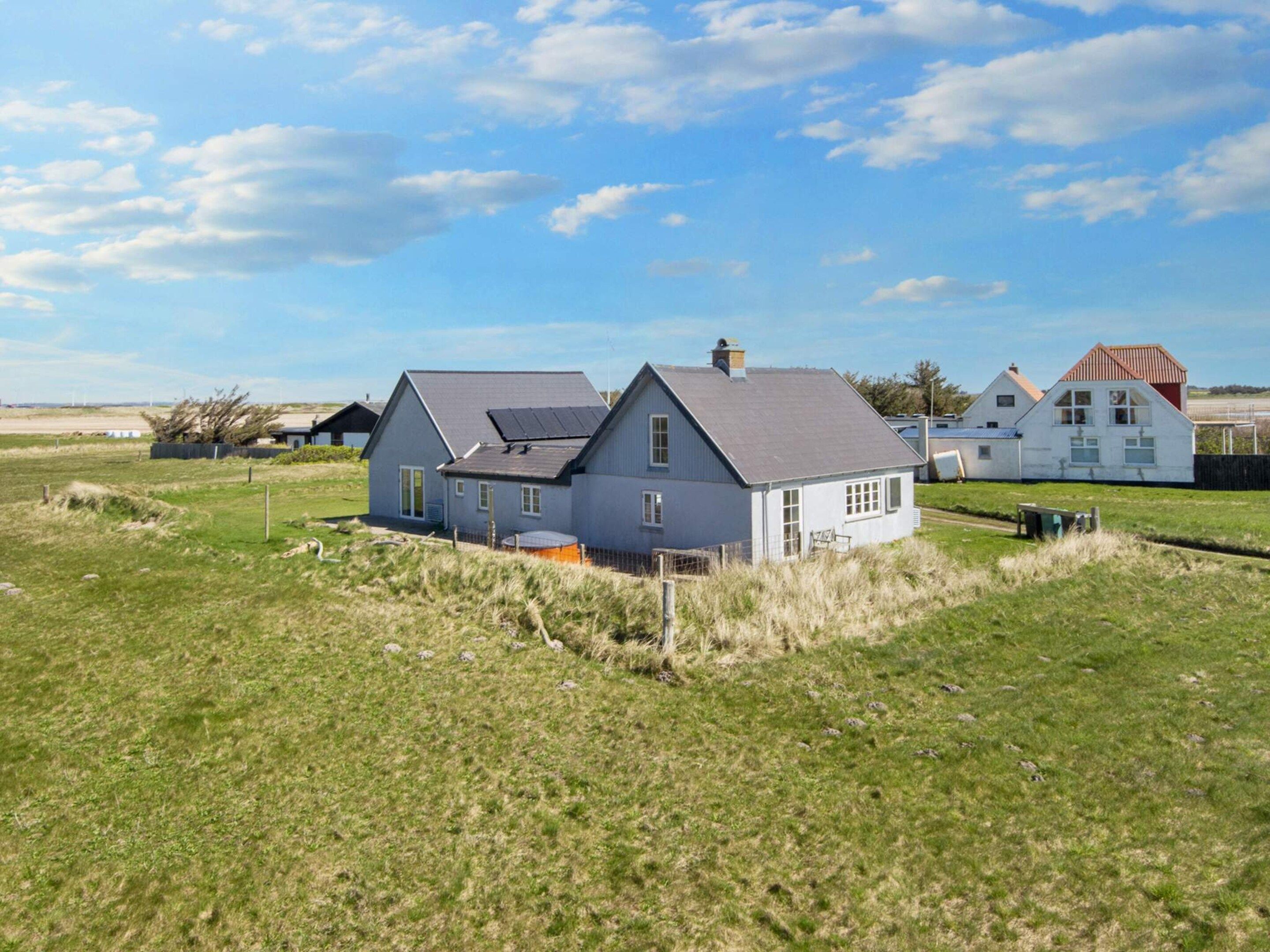 A residential area with houses, a grassy field, and a clear sky.