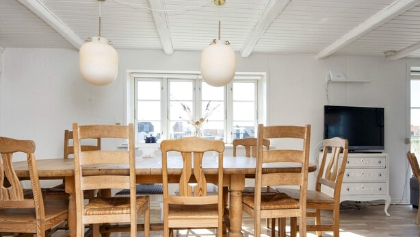 A dining area with a wooden table and chairs, a television, and a white cabinet. - 10 Person Holiday Home in Harboore (Harboore)