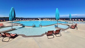 A large outdoor swimming pool with multiple lanes, surrounded by lounge chairs and umbrellas. - Bay-Life Living, Fenwick Island, Pool, Golf Cart, Bikes, Bay Beach, Gym, Kayak (Selbyville)