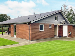 Un bâtiment à deux étages, doté d’un toit en pente, d’un patio couvert et d’un petit garage attenant.