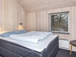 Una habitación con cama, ventana con persianas, lámpara de pared y radiador.