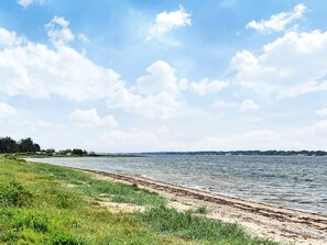 Vista a la orilla de un río con una playa de arena y riberas cubiertas de hierba.