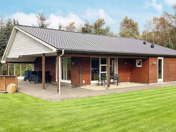 A single-story building with a covered patio area, large windows, and a flat roof.