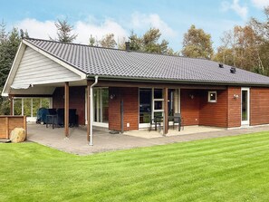 A single-story building with a covered patio area, a small attached garage, and a lawn in front. - 4 Star Holiday Home in Farso (Farso)