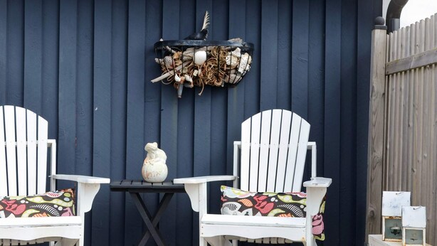 Two white Adirondack chairs with colorful cushions, a small table with a decorative vase, and a wall-mounted bird feeder. - 5 Person Holiday Home in Falkenberg (Falkenberg)