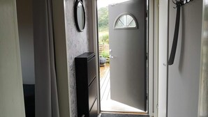 A hallway with a door leading outside, a coat rack, a mirror, and a small cabinet. - 5 Person Holiday Home in Falkenberg (Falkenberg)