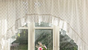 A window with a white frame, lace curtains, and a vase with flowers on the windowsill. - 4 Person Holiday Home in Ahus (Aahus)