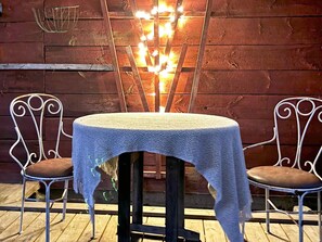 A table with a white tablecloth, two metal chairs with cushions, and a decorative light fixture in the background. - 4 Person Holiday Home in Ahus (Aahus)