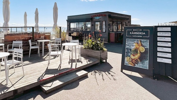 A café & bistro with outdoor seating, a menu board, and a view of the sea. - 4 Person Holiday Home in Ahus (Aahus)