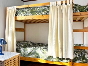 A bunk bed with a tropical leaf pattern bedspread, white curtains, and a small table with a lamp. - 4 Person Holiday Home in Ahus (Aahus)
