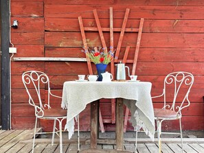 A rustic outdoor dining setup with a table, chairs, and a vase of flowers. - 4 Person Holiday Home in Ahus (Aahus)