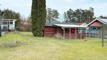 Una vivienda con garaje rojo, un porche cubierto y un alto pino.