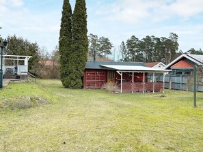 A residential property with a red garage, a covered porch, and a tall coniferous tree.