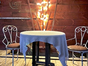 A table with a white tablecloth, two metal chairs with brown cushions, and a decorative light fixture in the background. - 4 Person Holiday Home in Ahus (Aahus)