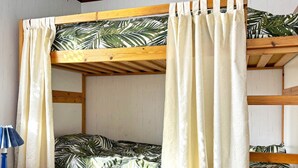 A bunk bed with a tropical leaf pattern bedspread, white curtains, and a small table with a lamp. - 4 Person Holiday Home in Ahus (Aahus)