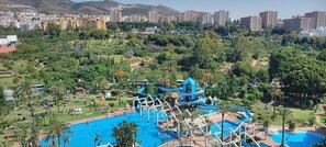A resort with a large swimming pool, water slides, and lush greenery.