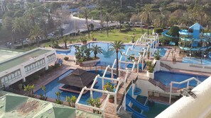 A resort with multiple swimming pools, palm trees, and a view of the surrounding area. - Beachfront Apartment With Terrace (Benalmádena)