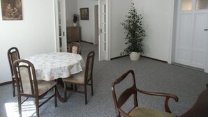 Ein Essbereich mit einem runden Tisch, vier Stühlen, einer Topfpflanze und einem Kronleuchter.