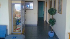 Ein Flur mit einer Glastrennwand, einem blauen Sofa, einer Topfpflanze und gerahmten Bildern an der Wand.