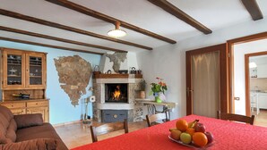 A cozy living room with a fireplace, a dining table with fruit, a sofa, and a cabinet. - Apartment in Croatia Near the Coast (Marcana)