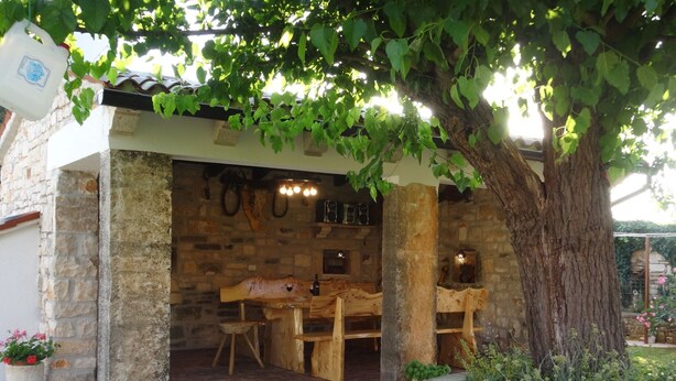 A rustic outdoor seating area with stone walls and wooden furniture. - Apartment in Croatia Near the Coast (Marcana)