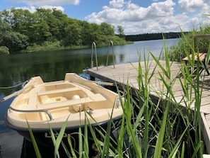 Un barco amarrado a un muelle de madera, con un río tranquilo y abundante vegetación al fondo.
