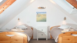 A cozy attic bedroom with two wooden beds, a small white nightstand, and a painting on the wall. - Casa Schalkenmehren Grande (Schalkenmehren)